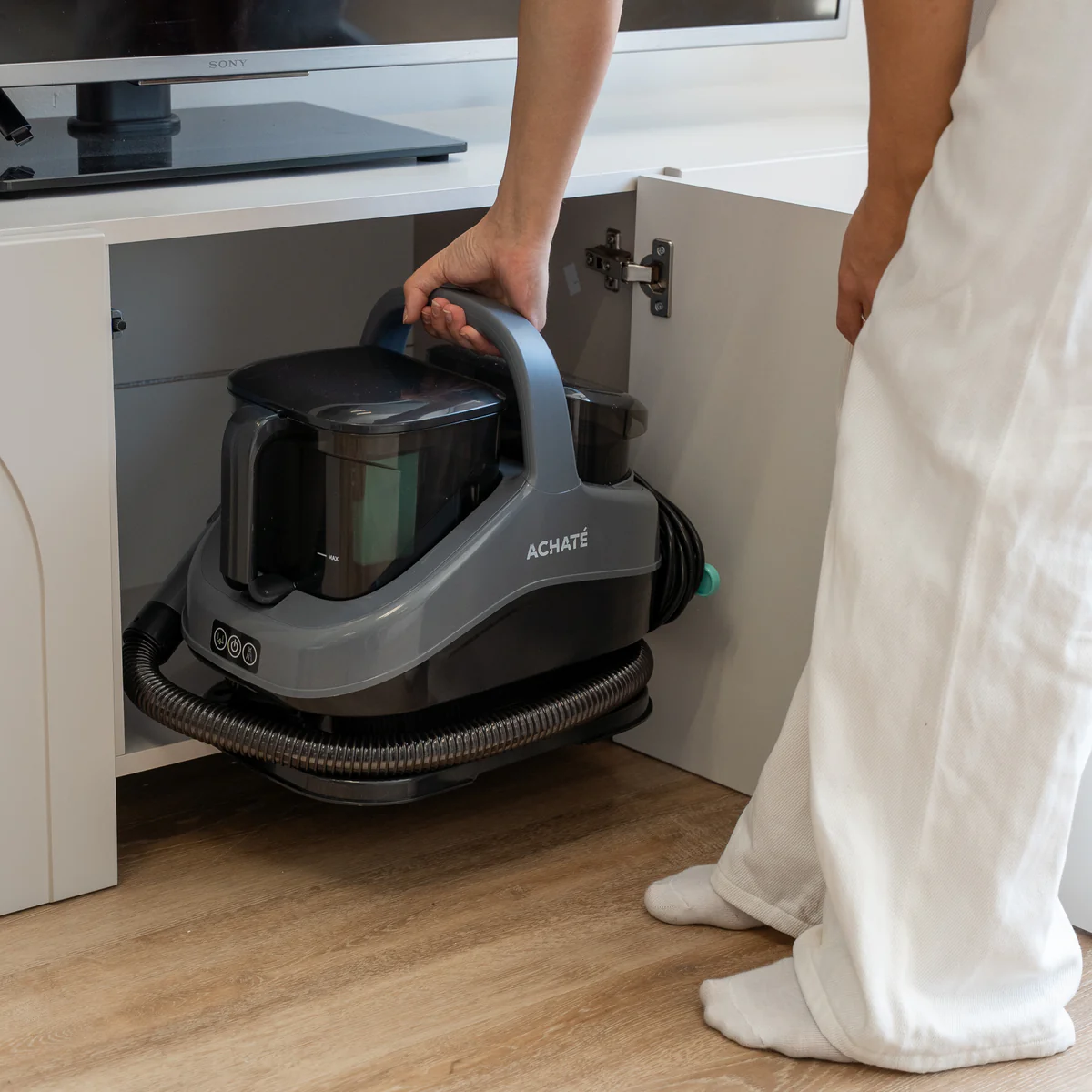 Person storing a vacuum cleaner in a cabinet.