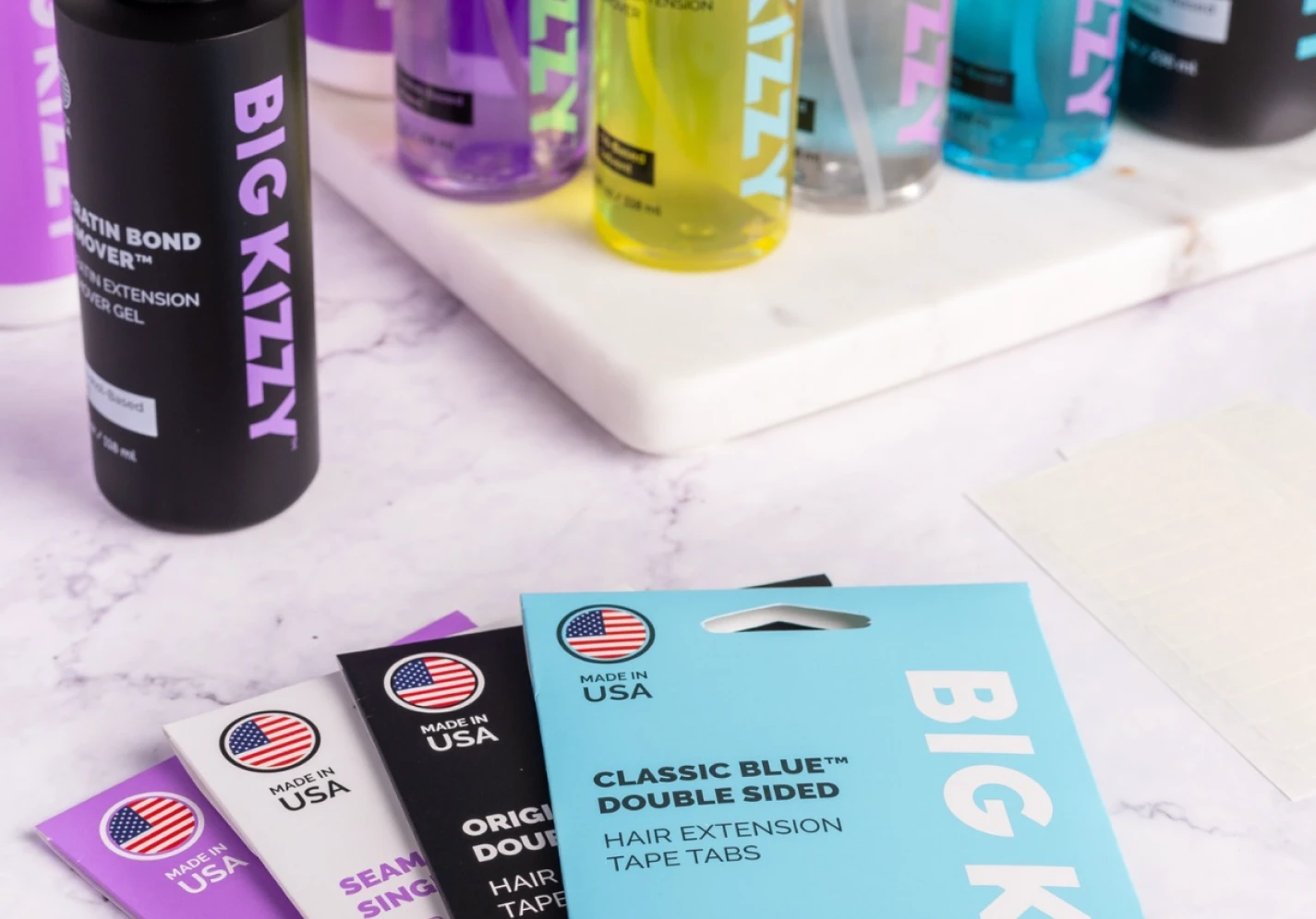 Assorted Big Kizzy hair extension products on a marble surface.