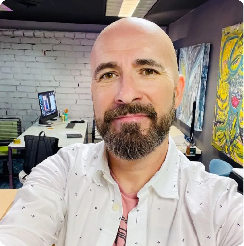 A person with a beard in an art-filled office space.