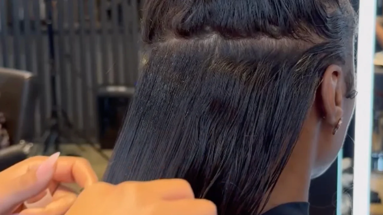 Close-up of hair extensions being applied to a person's head.