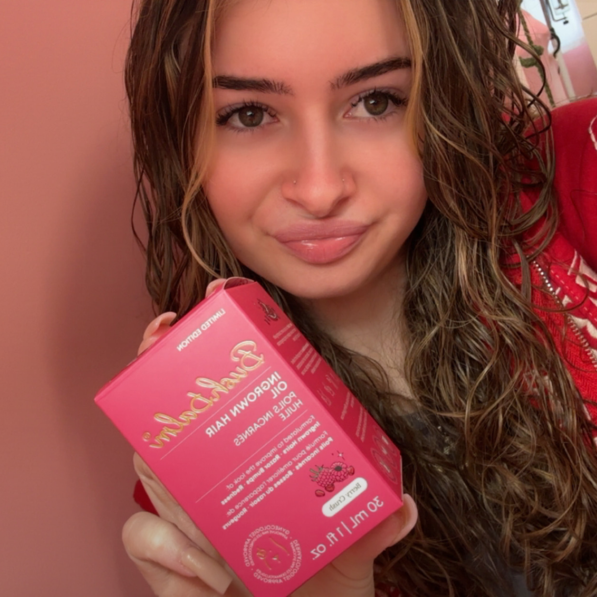Person holding a pink product box with text and graphics.