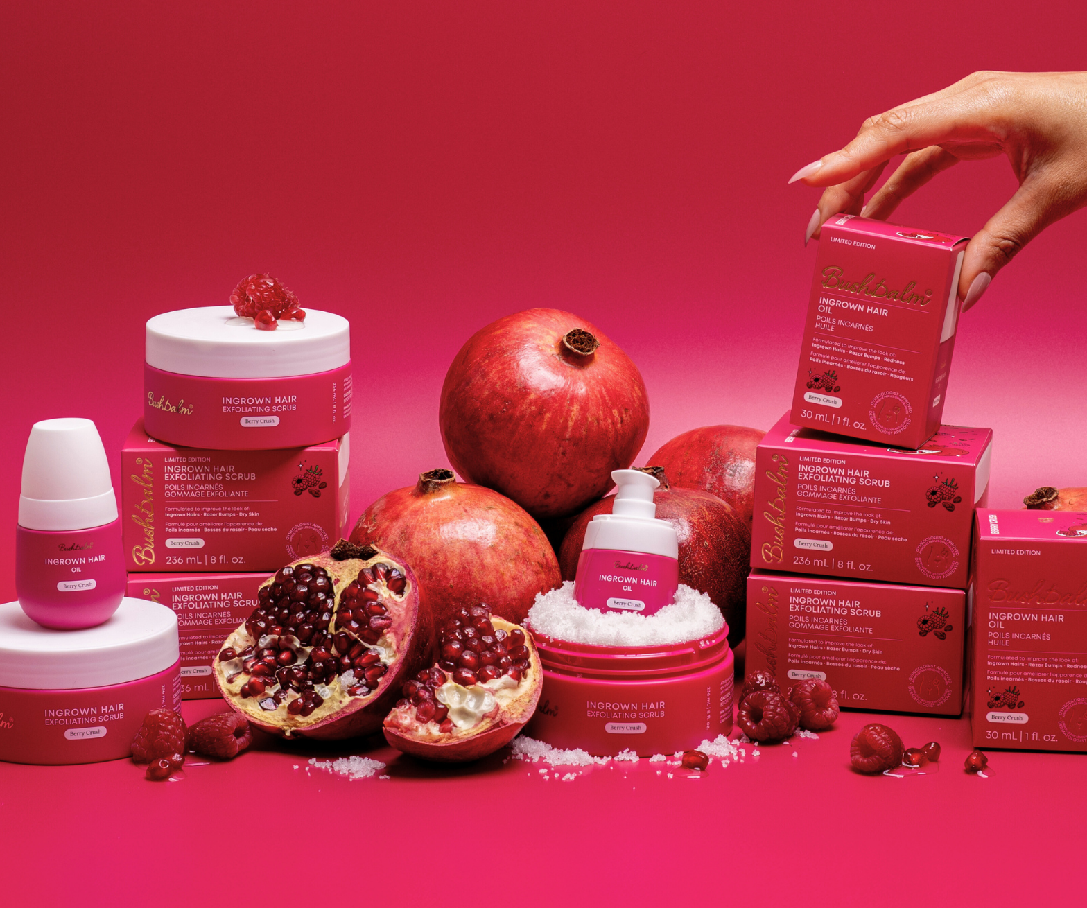 Pink bottles and boxes surrounded by pomegranates on a red background.