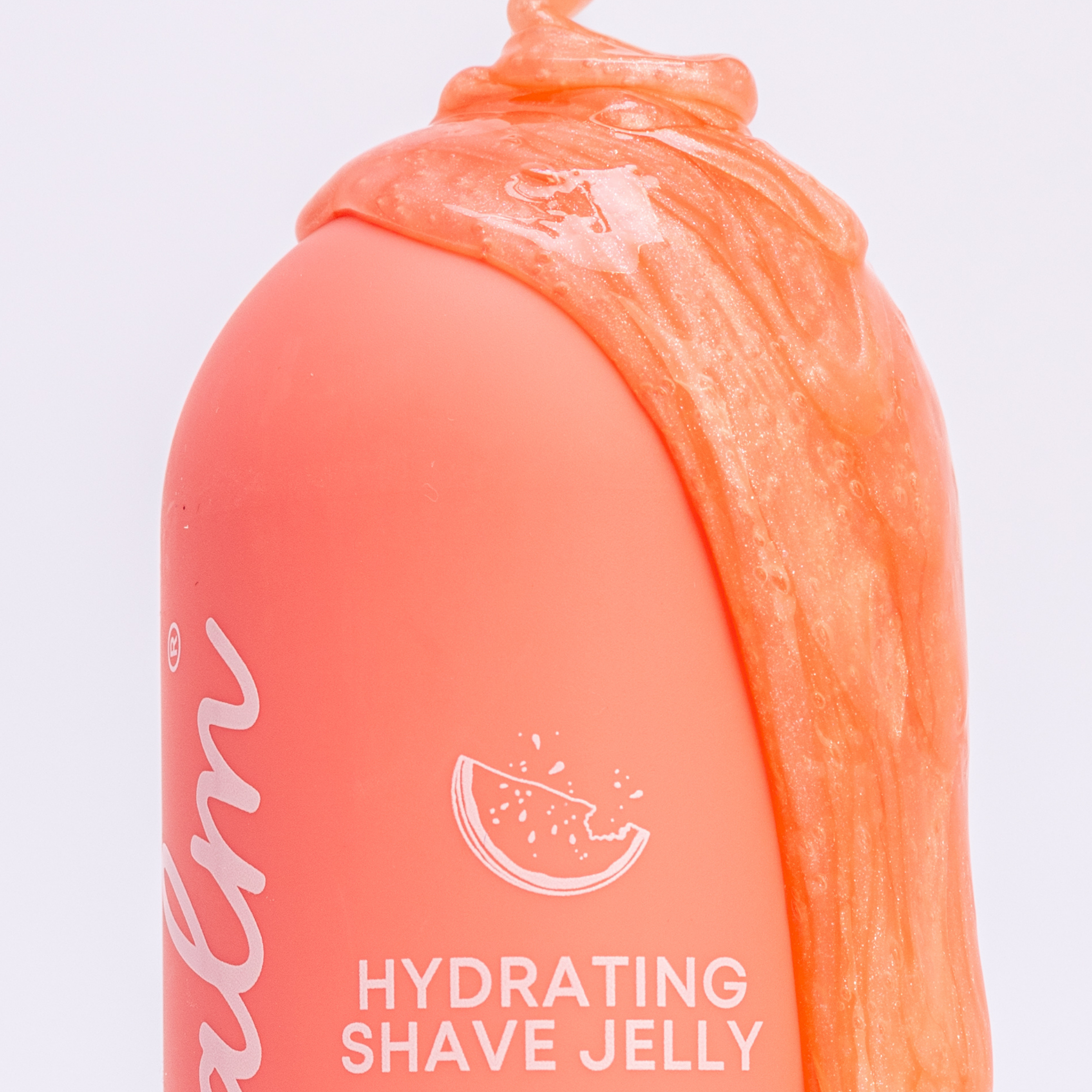 A close-up of a coral-colored bottle of Hydrating Shave Jelly with the shimmery product squeezed on top.