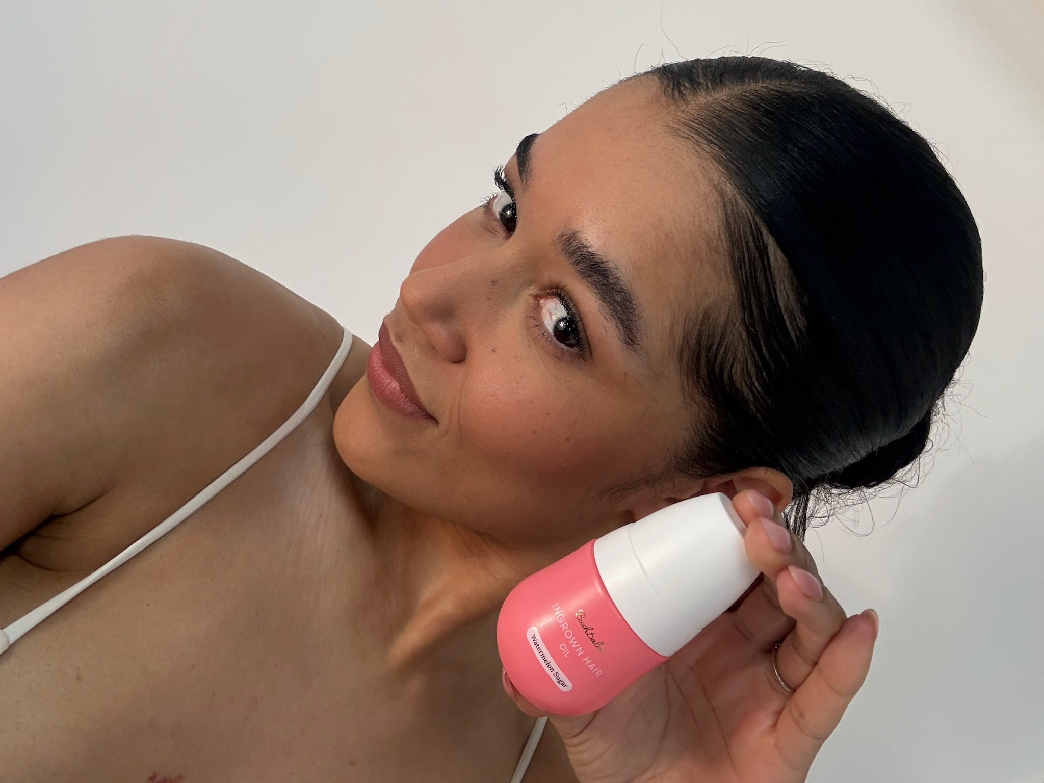 Person holding a pink bottle labeled 'Ingrown Hair' against a white background.