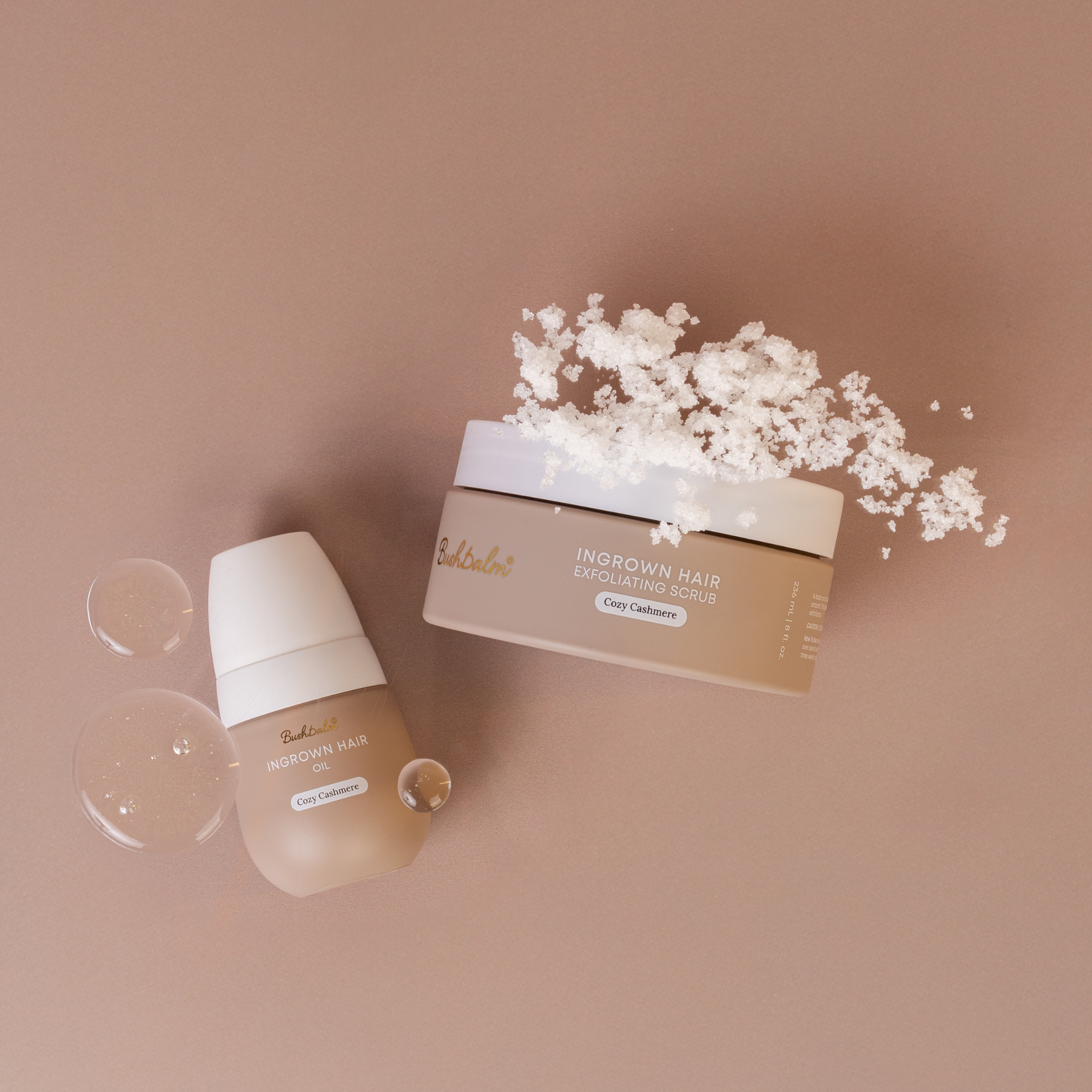 Two cosmetic containers labeled ingrown hair oil and scrub with scattered white particles.