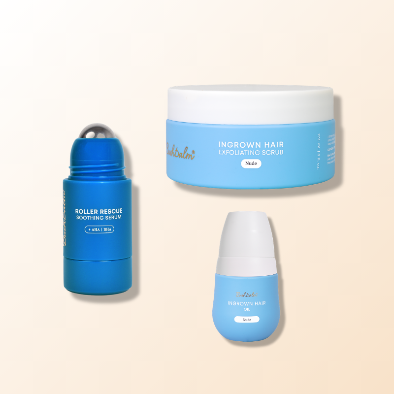 Three blue skincare products, a rollerball serum, an exfoliating scrub, and an oil, on a cream background.