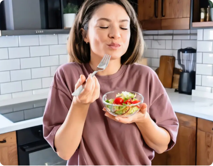 Person enjoying a salad in a modern kitchen.