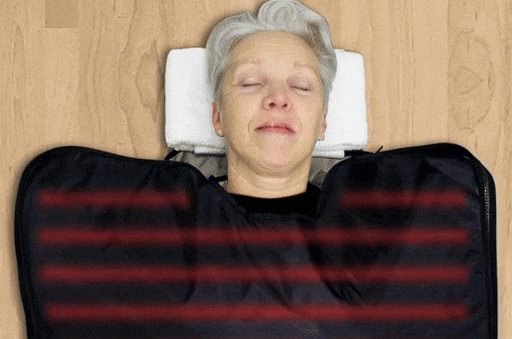 Person lying with black cover and red lights on upper body.