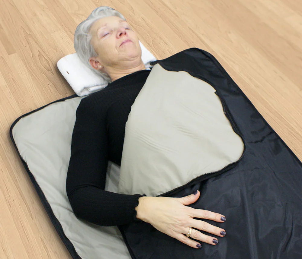 Person lying in a sleeping bag on a wooden floor.
