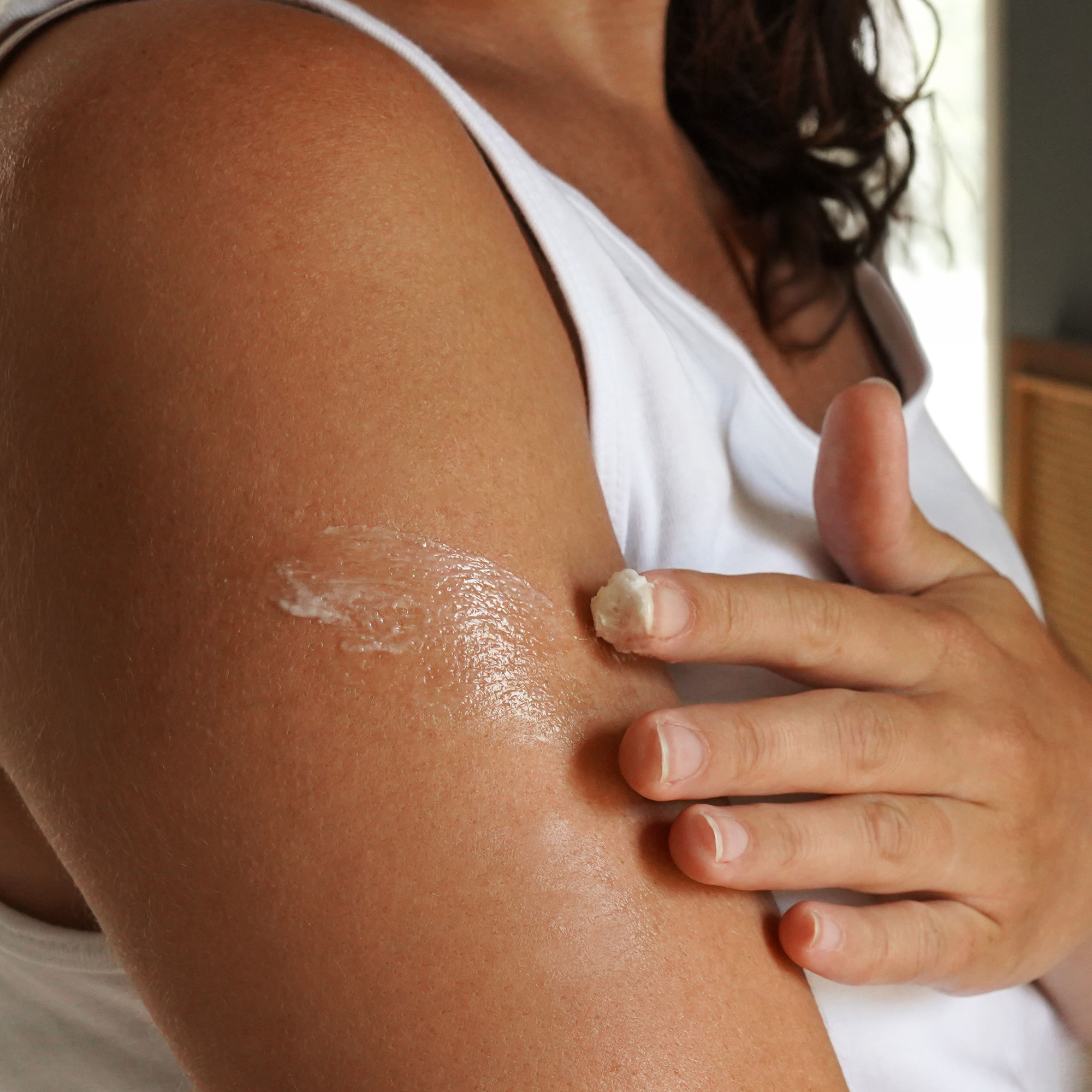Person applying cream to their upper arm.