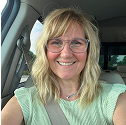 Person with glasses smiling in a car.