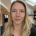 A woman with long blonde hair in a room with skylights and modern decor.