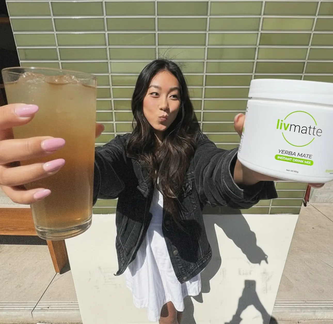 Person holding a drink and a container labeled 'livmatte.'