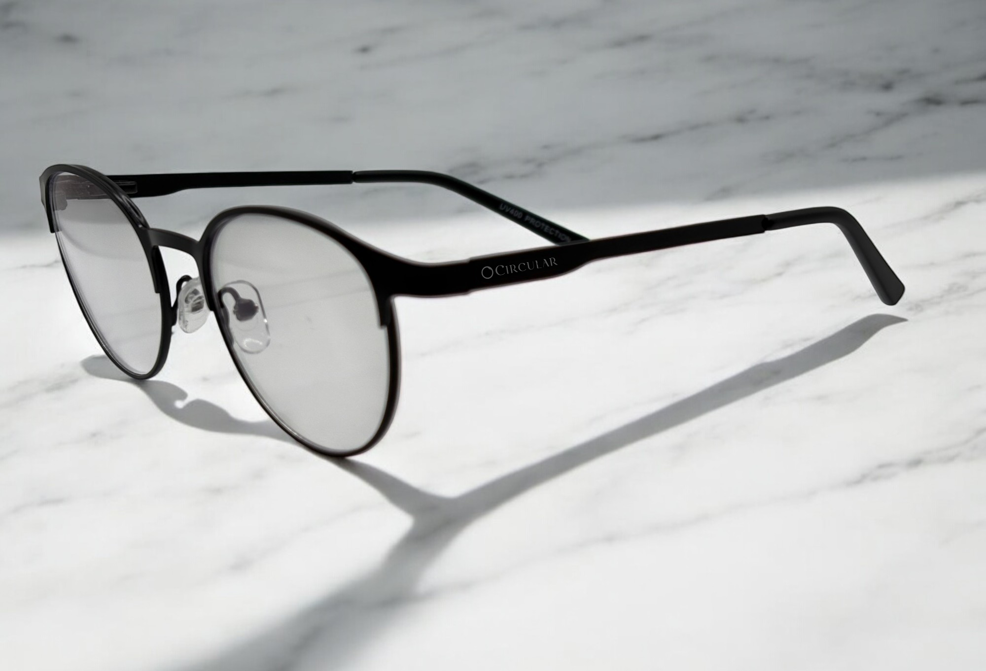 Black-rimmed eyeglasses with clear lenses on a marble surface.