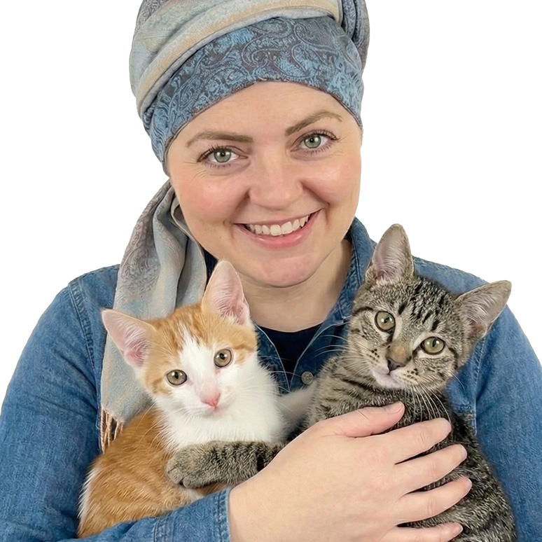 Person smiling, holding two kittens closely, one orange and white, the other tabby.