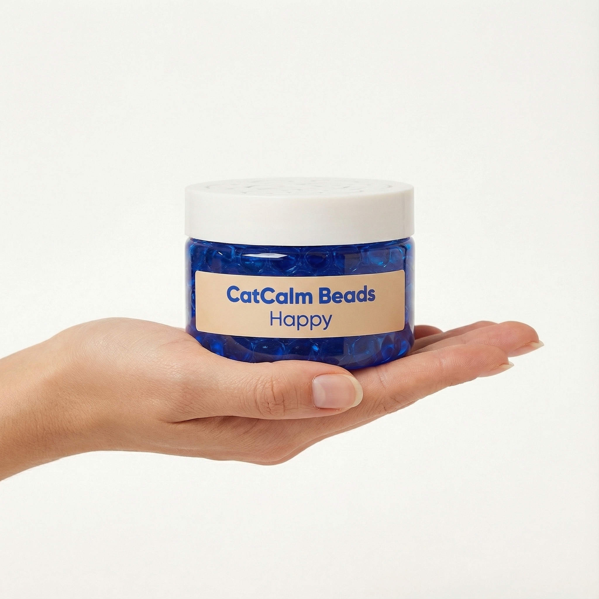 A hand holds a jar of CatCalm Beads filled with small blue beads against a white background.