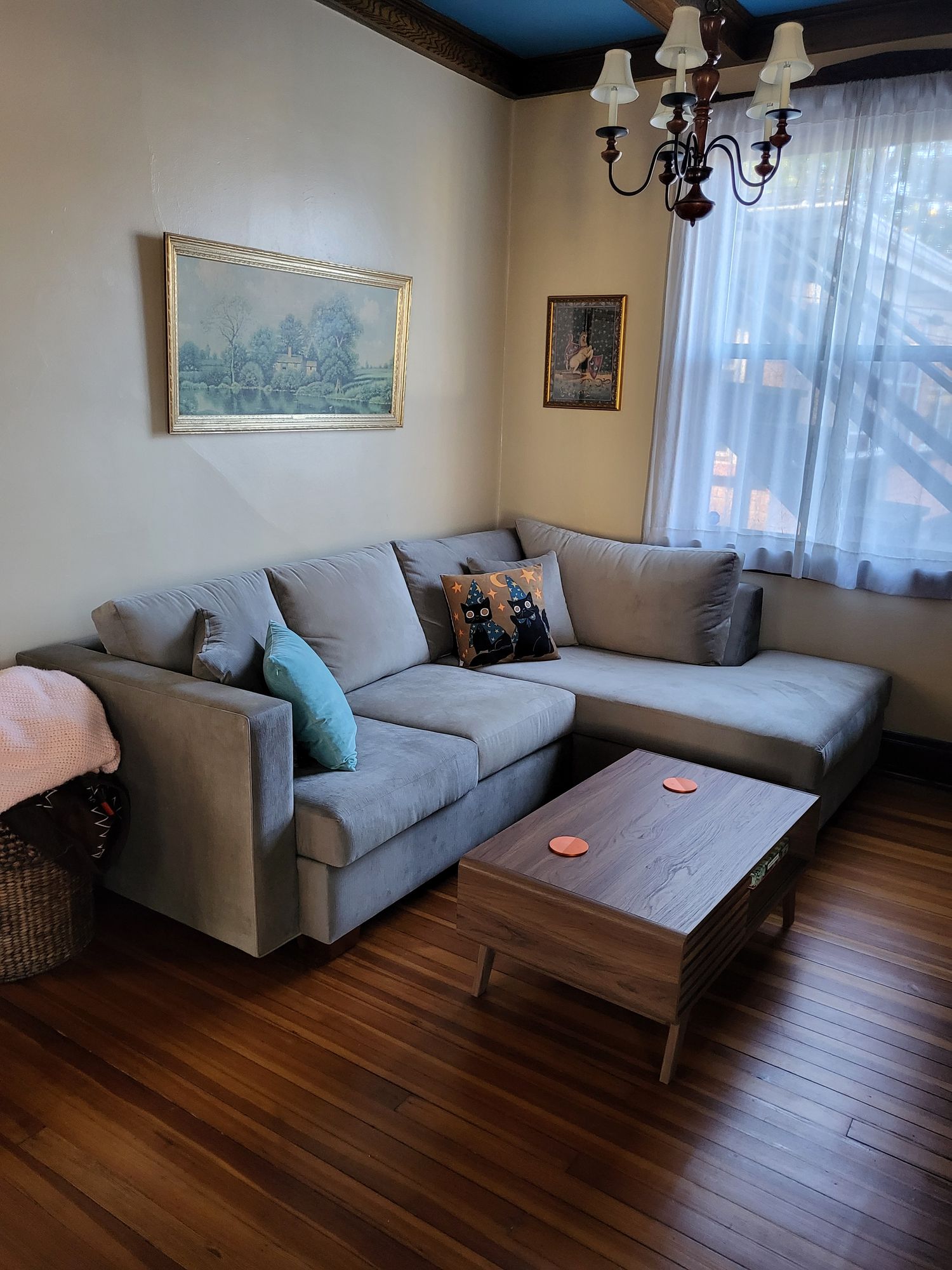 A living room with a grey sectional sofa, a wooden coffee table, and framed art on the wall.