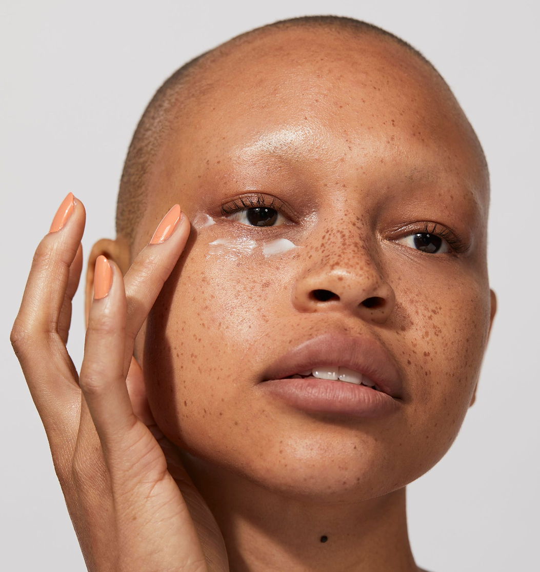 Person applying cream under their eye with fingers.
