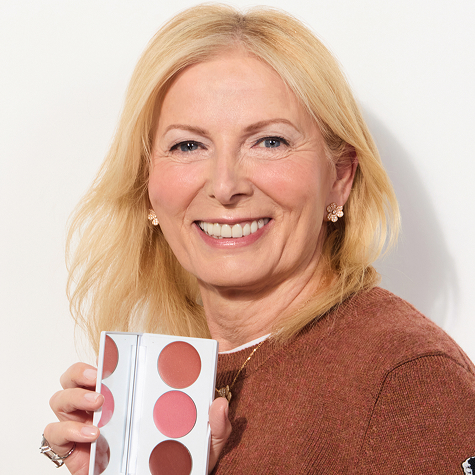 Smiling person holding a makeup palette with four shades.