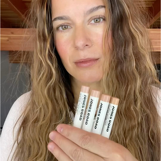 Person holding four Jones Road beauty products.
