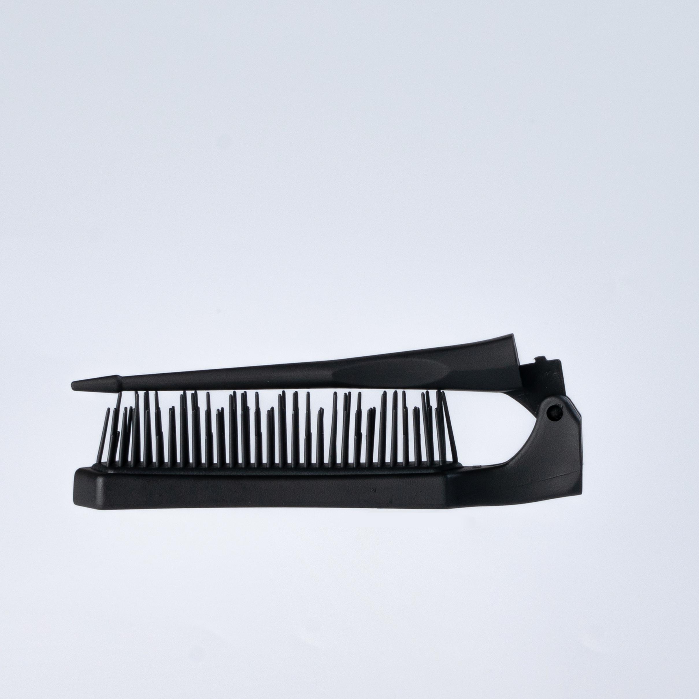 Black folding hairbrush with bristles, closed position.