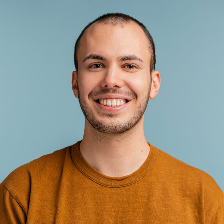 Smiling man in a brown shirt against a blue background.