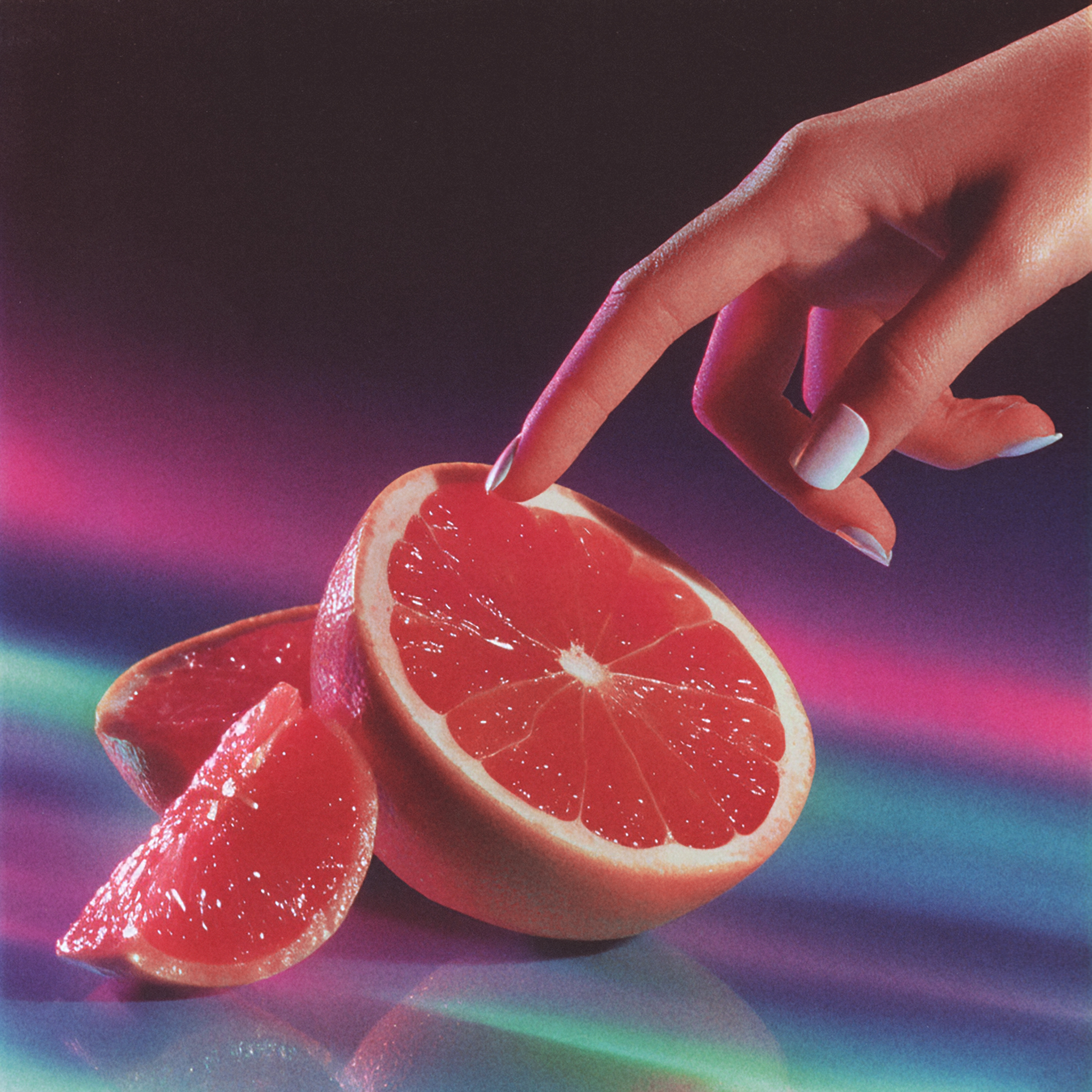 Hand touching a sliced grapefruit with colorful background.