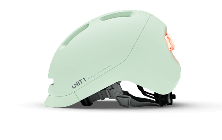 Light green bicycle helmet with a rear light, side view.
