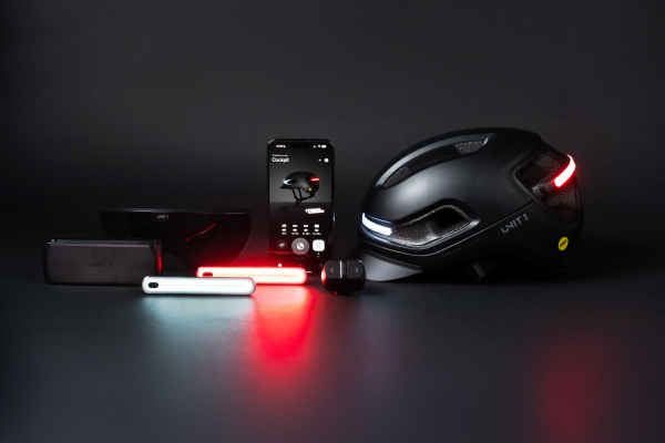 Black smart helmet with red and white lights, surrounding tech gadgets.
