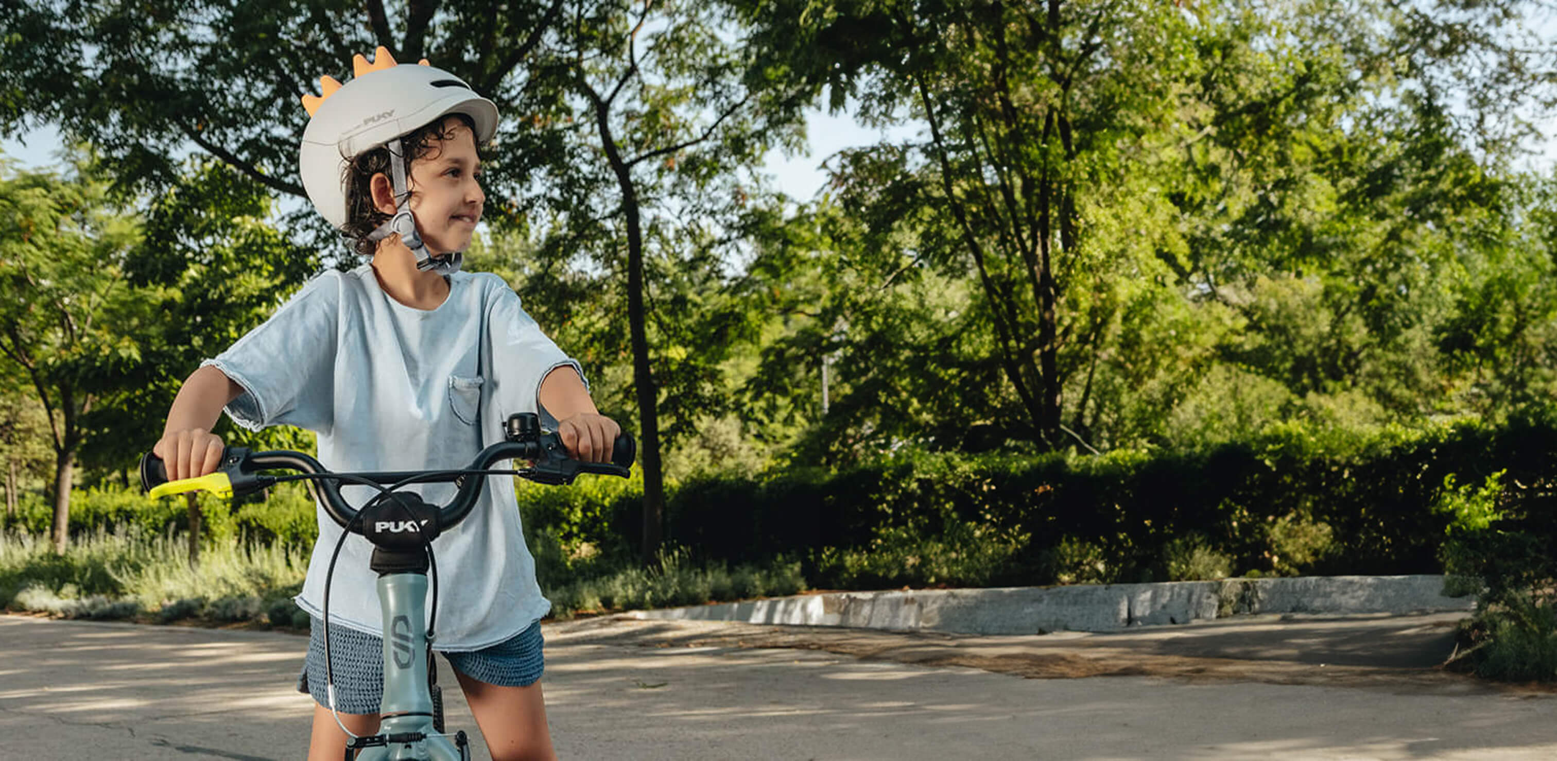 Et barn med hjelm cykler i en park.