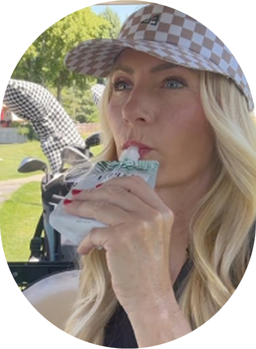 Person in a checkered cap drinking from a pouch outdoors.