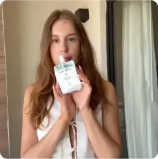 Woman holding a skincare product in a room with natural light.