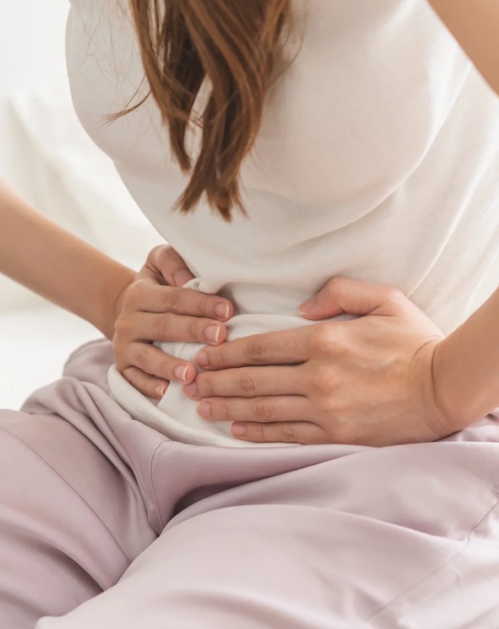 Person holding their stomach with both hands.