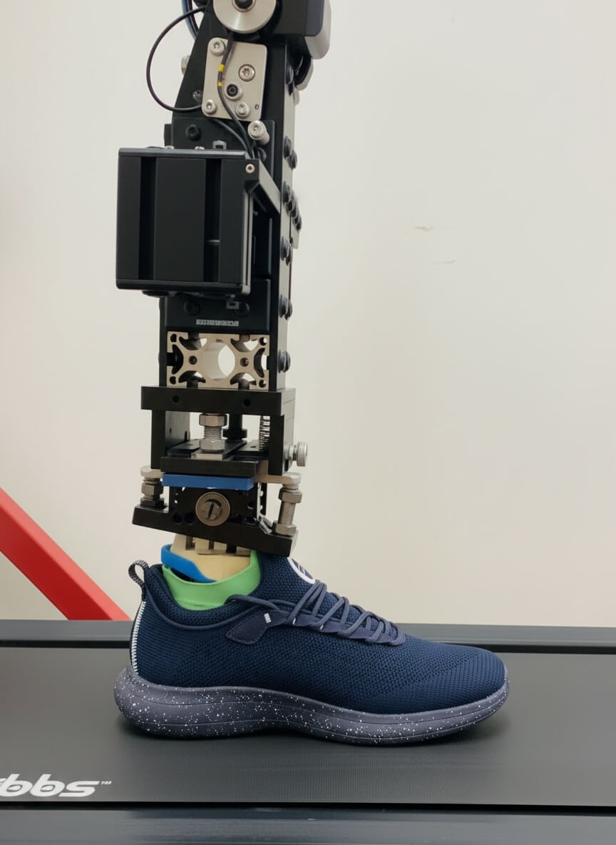 Robotic device testing a navy sneaker on a treadmill.