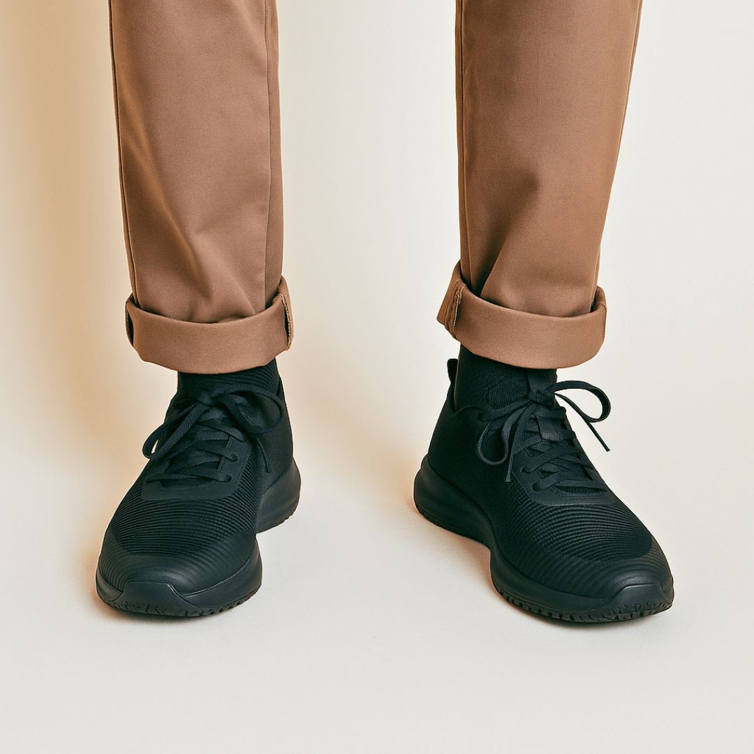 Person wearing black sneakers and rolled-up brown pants.