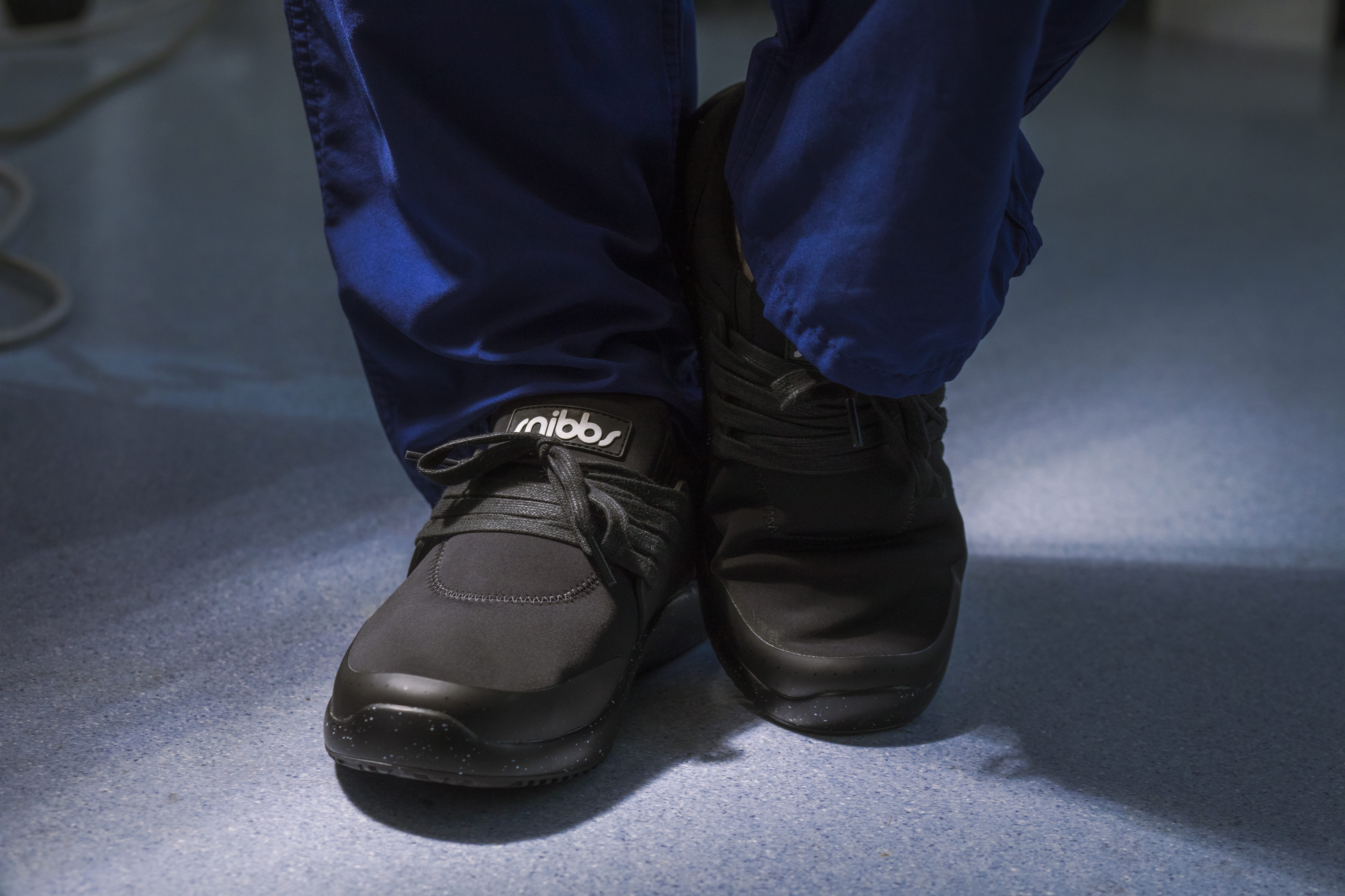 Person wearing black shoes and blue pants on a blue floor.