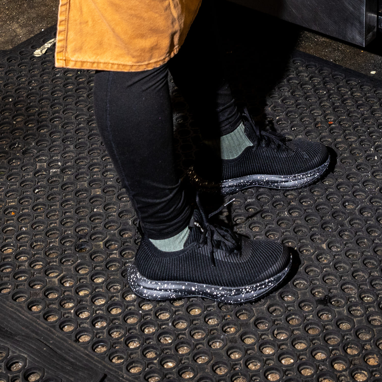 Person wearing black sneakers and leggings on a rubber mat.