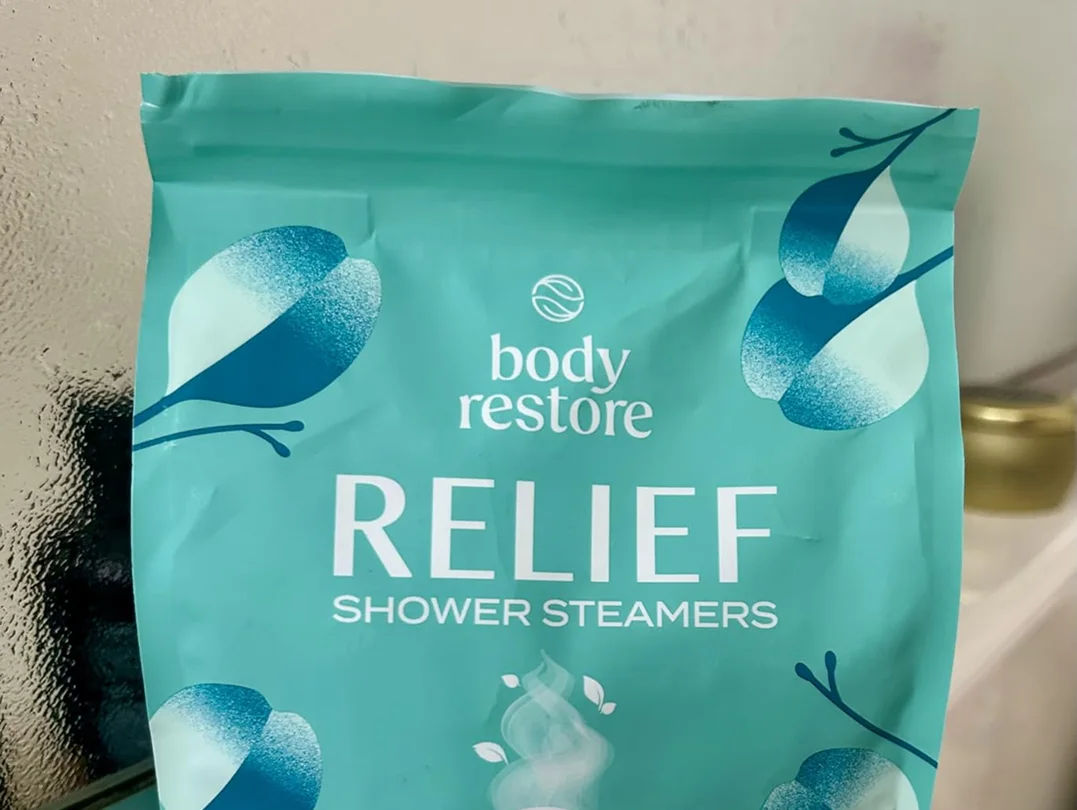 A close-up of a teal pouch of Body Restore Relief Shower Steamers.
