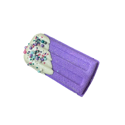Purple popsicle-shaped bath bomb with white frosting and colorful sprinkles.