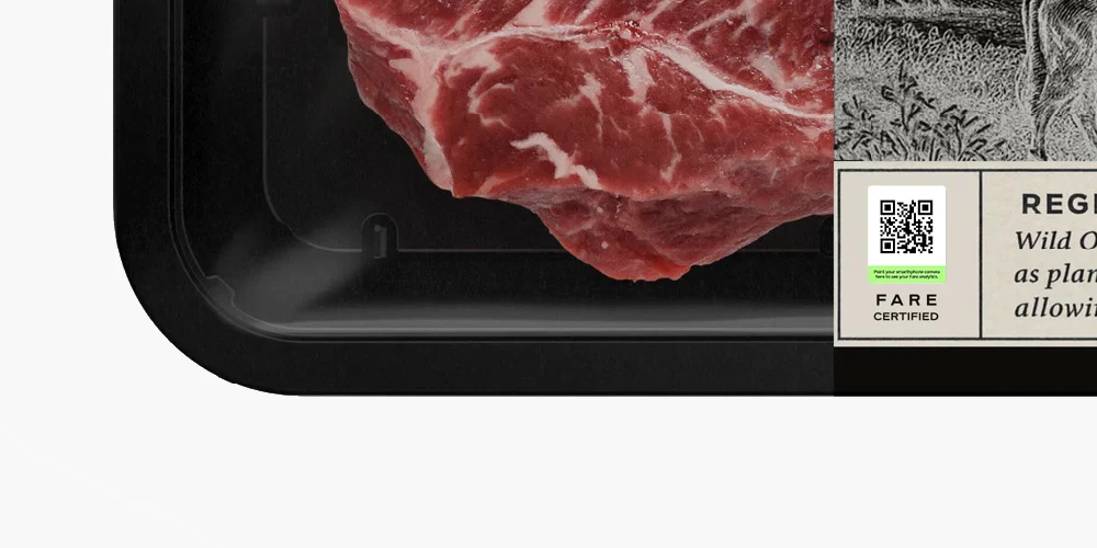 A close-up of a packaged raw steak in a black tray with a label and QR code.