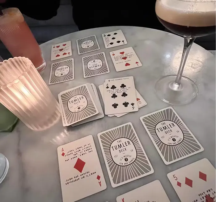 Playing cards on a table with two glasses and a candle.