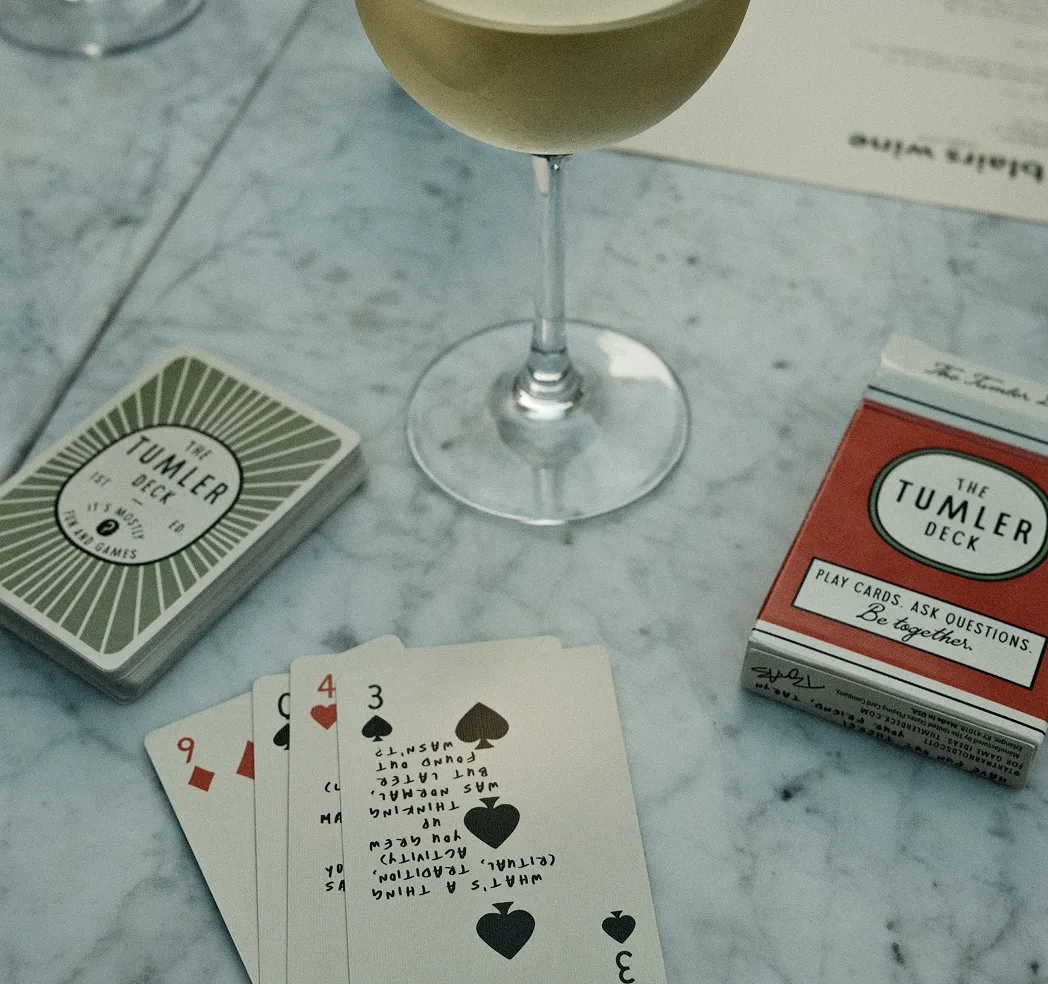 Playing cards and a wine glass on a marble table.