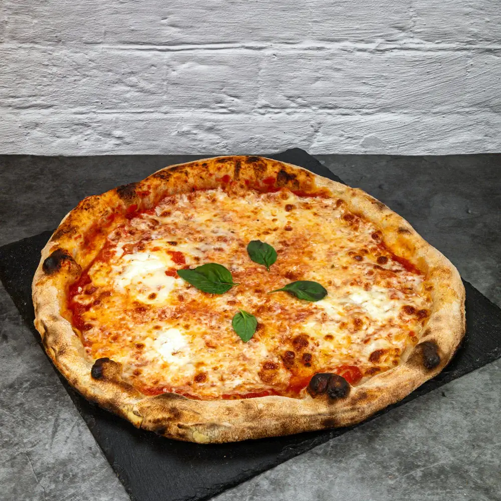 A margherita pizza with basil leaves on a dark surface.
