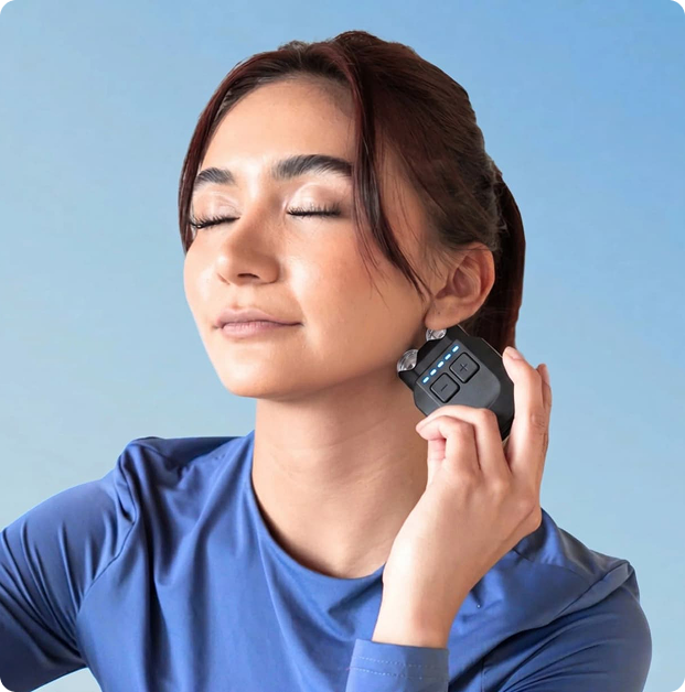 A woman with her eyes closed holds a small black facial toning device to her jawline.