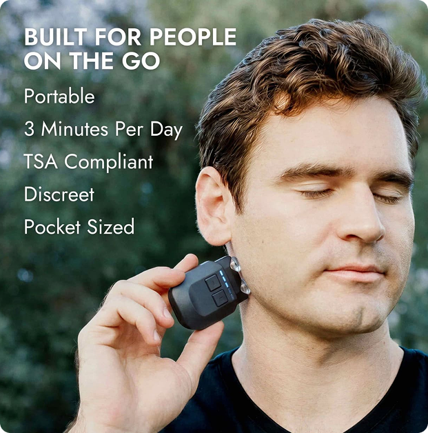 A man with his eyes closed holds a small black electronic device to his jawline.