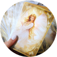 A hand holding angel-themed tarot cards with golden artwork.