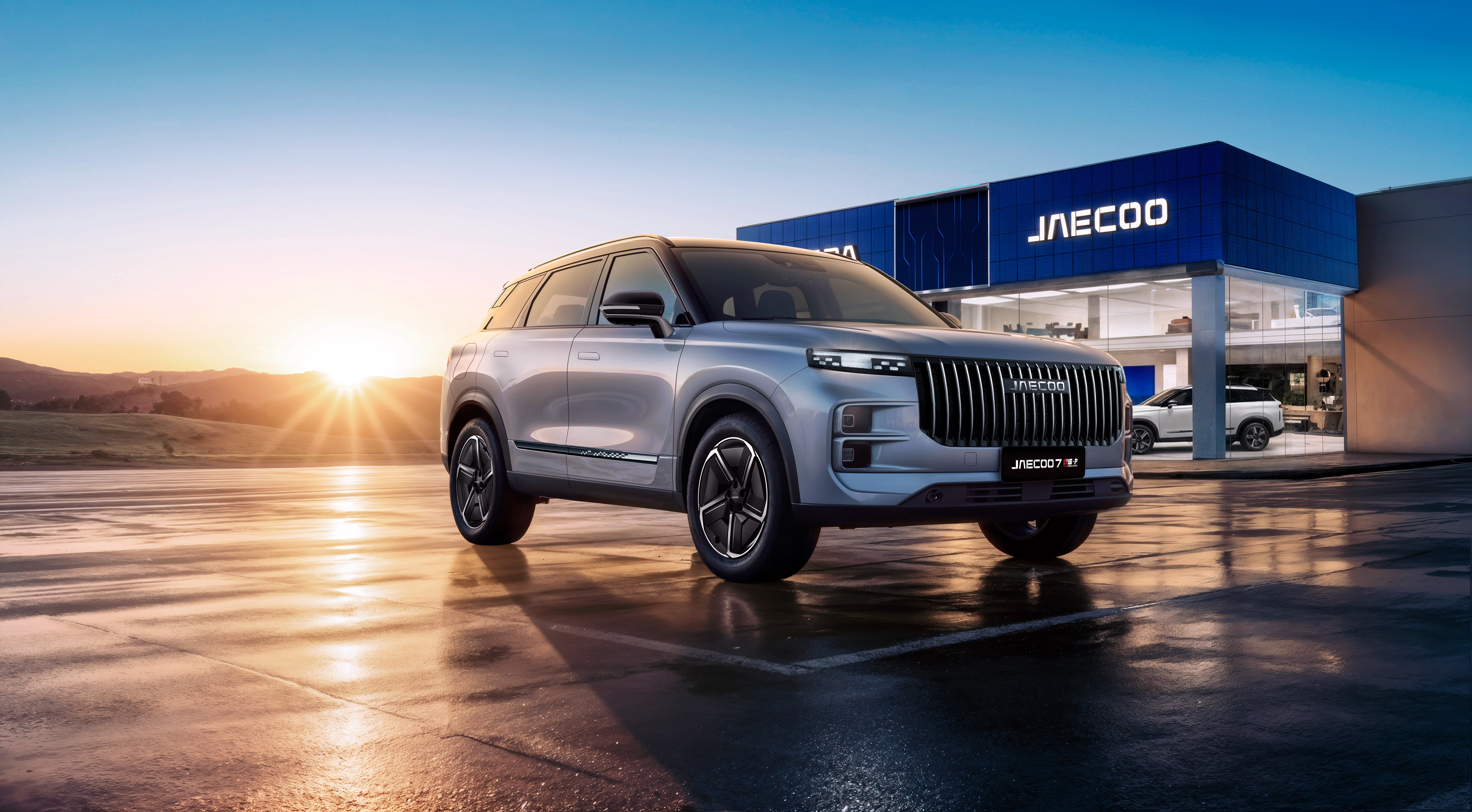 A silver Jaecoo SUV parked on wet ground in front of a modern dealership at sunrise.