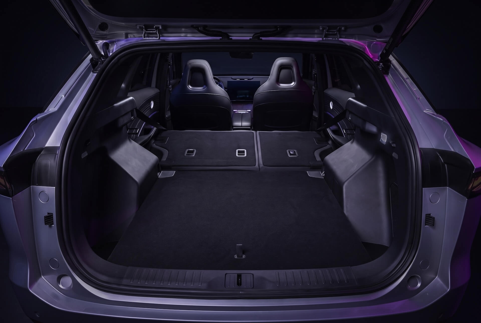 A view into the empty cargo area of a modern car with the hatchback open and seats folded down.