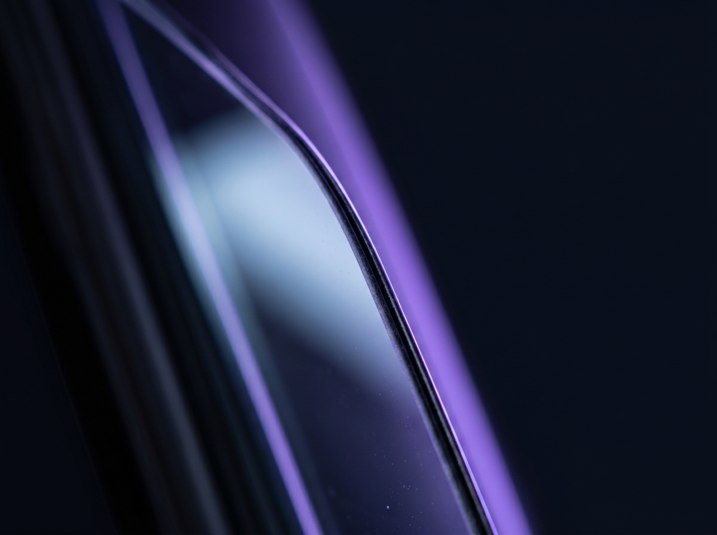 An abstract close-up of a curved, reflective surface with streaks of purple and blue light.