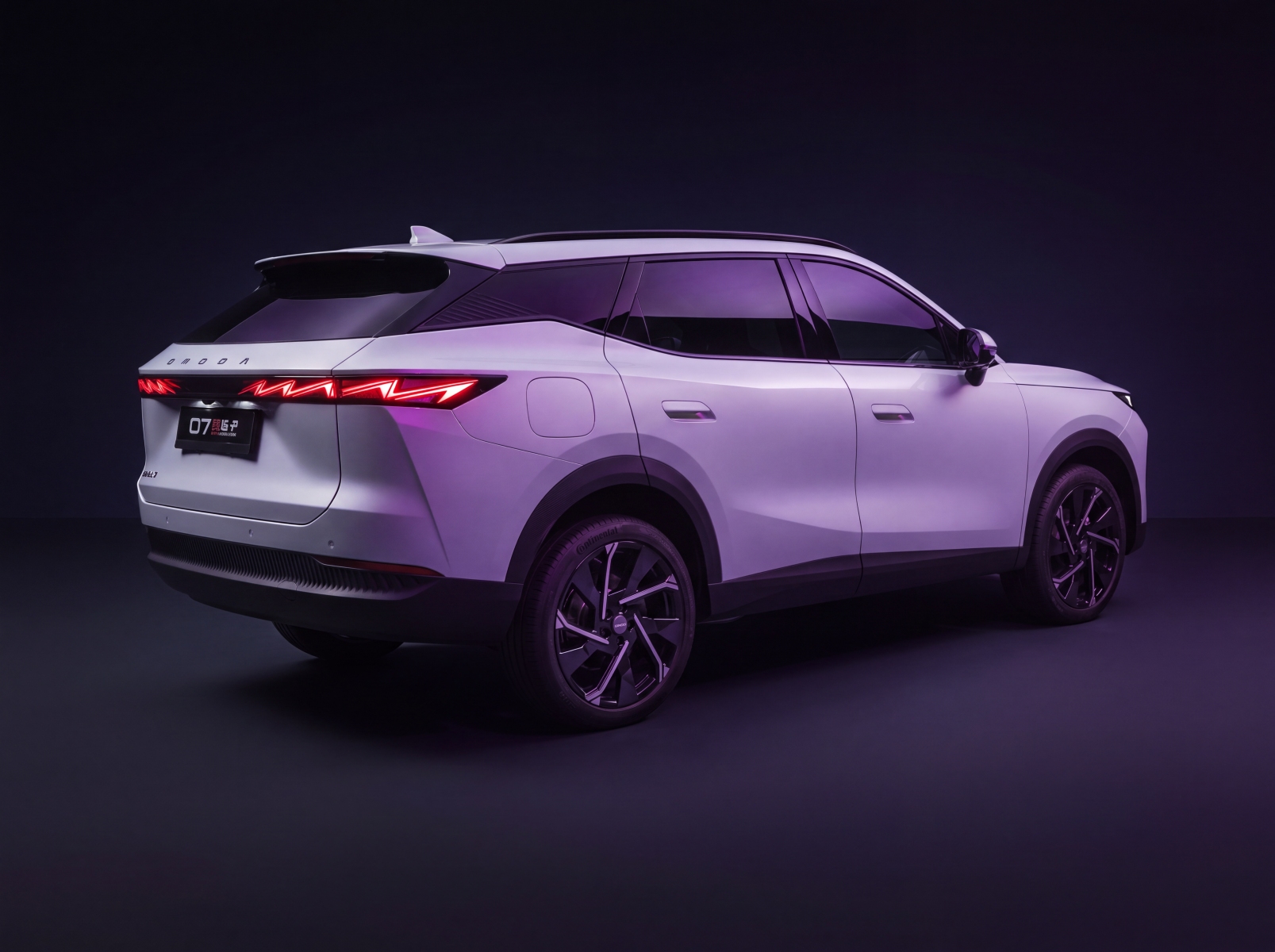 A modern white SUV is shown from the rear three-quarter view in a studio with purple lighting.